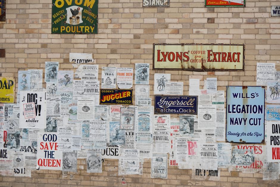 Colección de carteles vintage en una pared de ladrillo, mostrando anuncios históricos