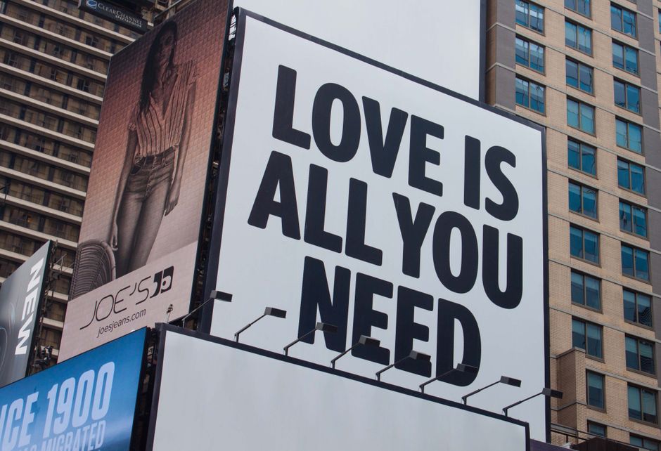 Gran valla publicitaria de la ciudad con el mensaje Love Is All You Need en una calle de Nueva York